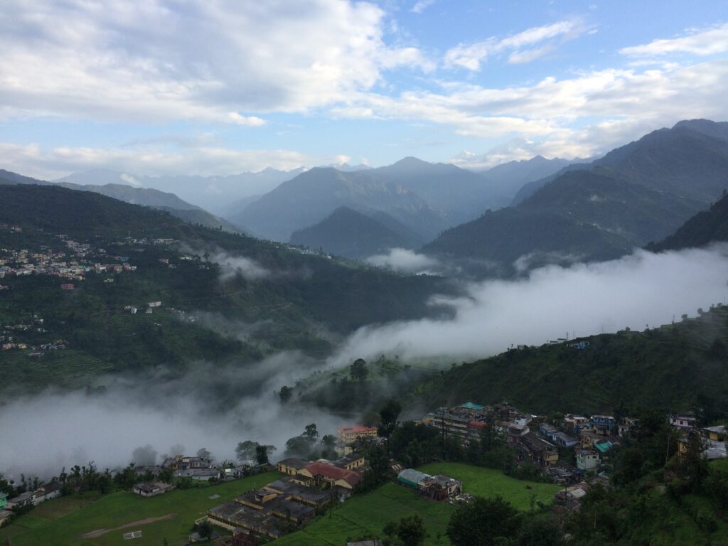 Misty morning view of Chopta Valley in Ukhimath, Uttarakhand with mountain ranges and scattered villages