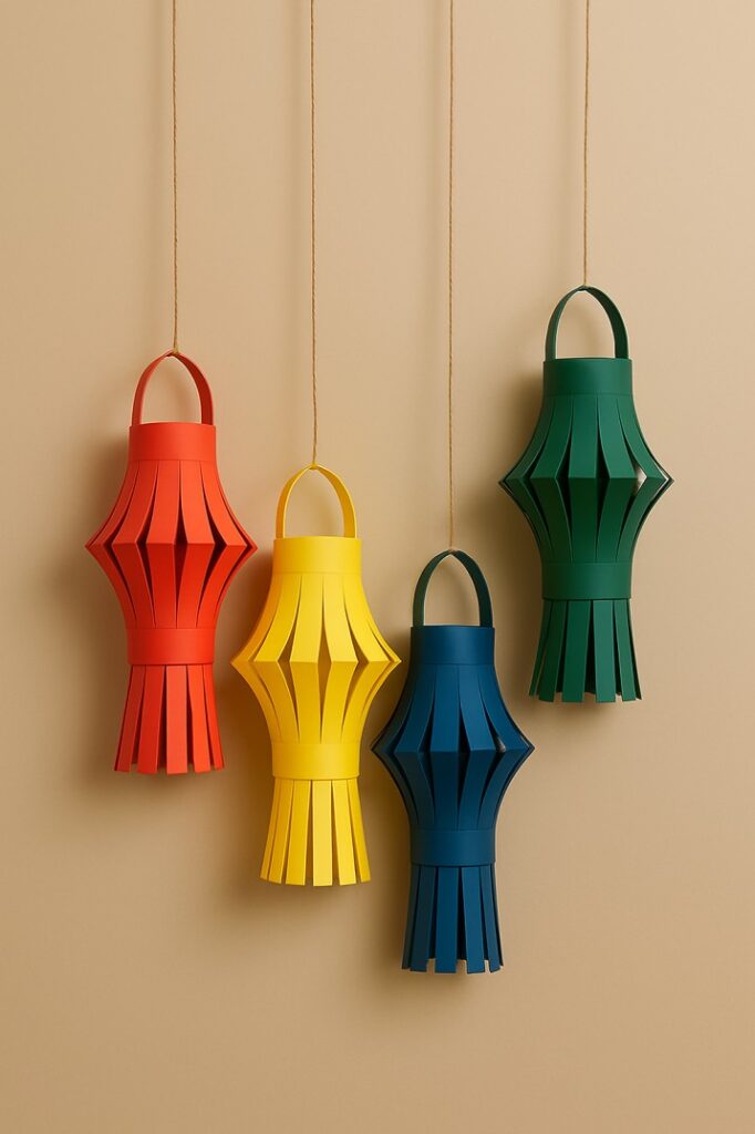Four colorful paper lanterns in red, yellow, blue, and green hanging on strings against a beige wall, showcasing paper wall hanging craft