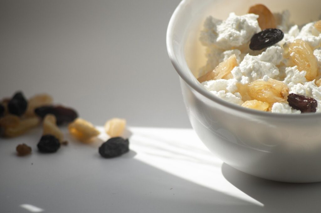 A white bowl of cottage cheese & Pineapple topped with golden and black raisins – healthy snacks for kids