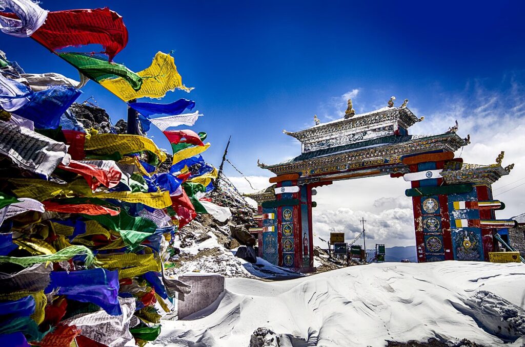 Colorful prayer flags fluttering near the ornate Tawang Gate in snowy Arunachal Pradesh, India