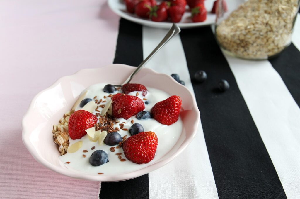 A bowl of yogurt topped with strawberries, blueberries, granola, and flax seeds, served as healthy snacks for kids.
