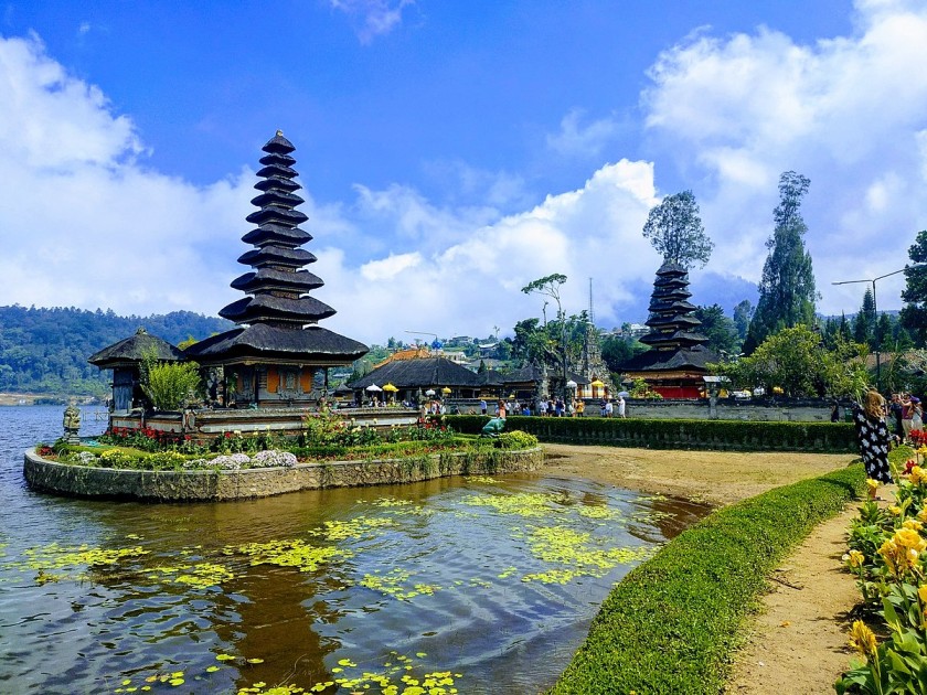 Scenic view of a traditional Balinese temple surrounded by water and lush greenery, representing Bali as a budget-friendly honeymoon destination.