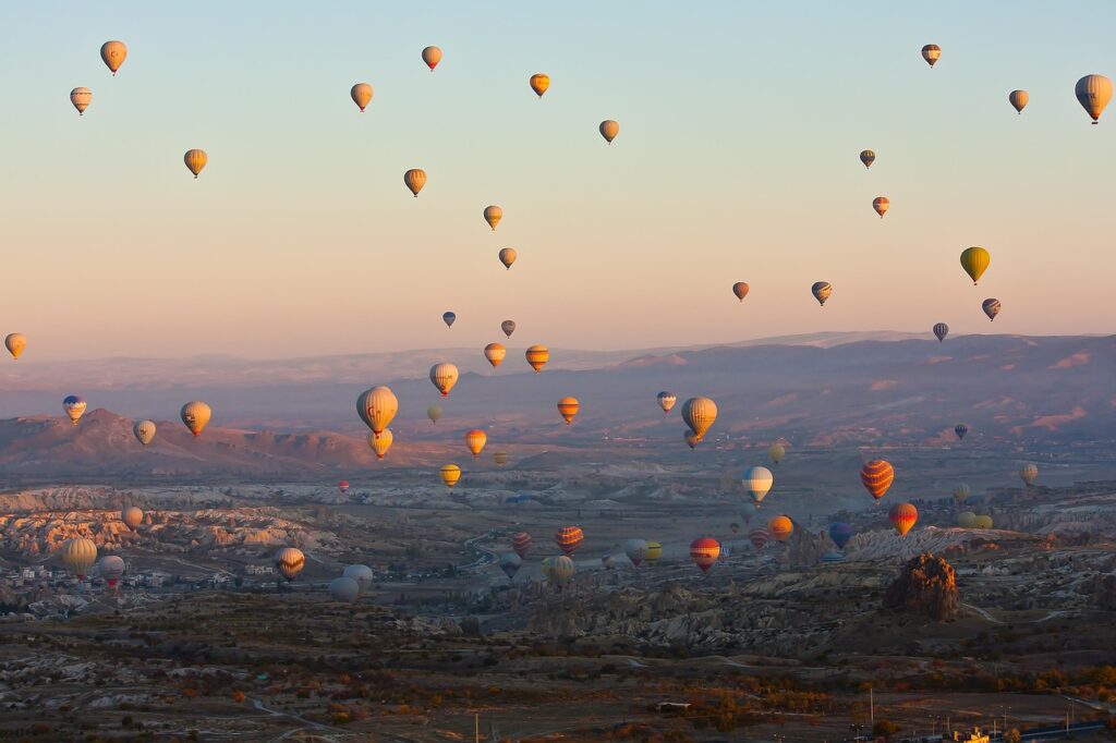 Most beautiful places in the world – colorful hot air balloons soaring over the unique rock formations and valleys of Cappadocia, Turkey at sunrise.
