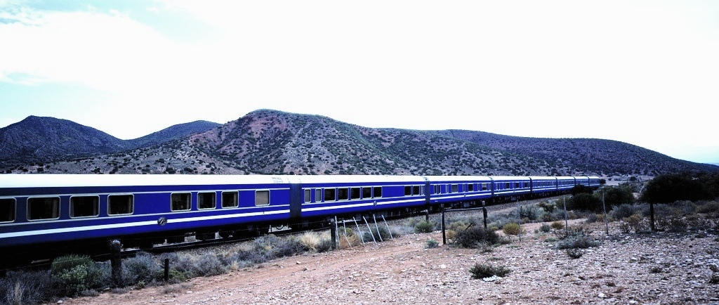 The Blue Train in South Africa, one of the most scenic and luxurious train rides in the world, passing through desert landscapes and vineyards towards Cape Town.