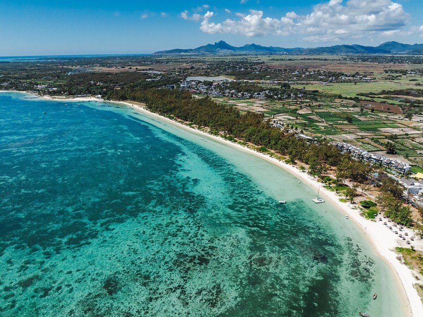 Mauritius island with turquoise lagoons, coral reefs, and palm-fringed beaches, surrounded by lush green landscapes and vibrant tropical scenery.