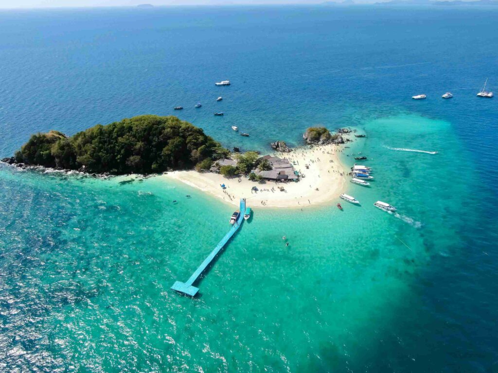 Phuket, Thailand featuring a tropical beach with long-tail boats, clear blue water, and limestone cliffs under a sunny sky.